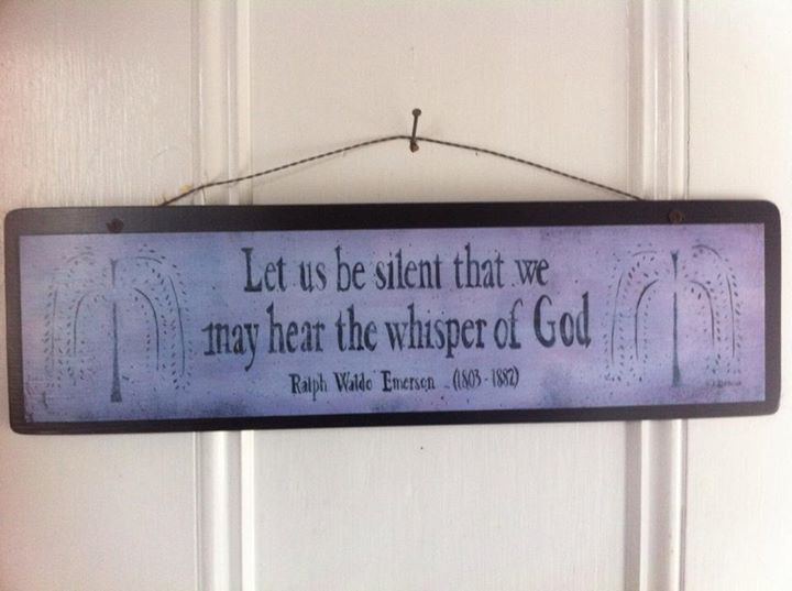 Wooden sign on a white door that leads into the Worship area of the meetinghouse. The sign reads: "Let us be silent that we may hear the whisper of God". Underneath the text, it reads: "Ralph Waldo Emerson (1803-1887)".
